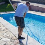 hombre hace el mantenimiento de una piscina
